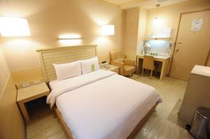 Habitación de hotel con cama grande y escritorio. en Kindness Hotel - Jhong Jheng en Kaohsiung