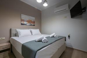 a bedroom with a large white bed with towels on it at OLYMPIA ROOMS in Myrina