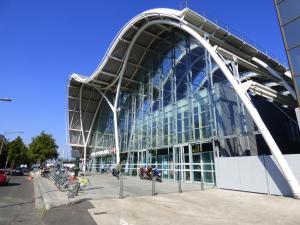 奧爾良的住宿－37m² lumineux face gare SNCF + café et thé offerts，一座大型玻璃建筑,前面停有摩托车