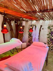 two beds in a room with pink sheets and lights at Hotel Boutique Santa Clara Mesa de los Santos in Los Santos