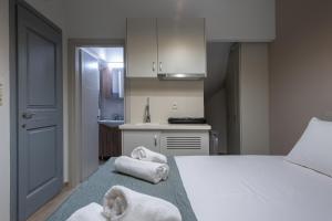 a bedroom with towels on a bed and a kitchen at OLYMPIA ROOMS in Myrina