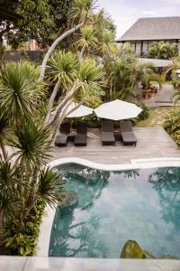 een zwembad met een tafel en stoelen en palmbomen bij Wave House - Surf Camp in Canggu
