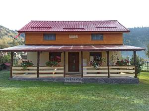 une petite maison avec une grande terrasse couverte dans un champ dans l'établissement Casa Prundari Nicu și Mirela, à Poiana Teiului