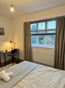 Schlafzimmer mit einem Bett, einem Schreibtisch und einem Fenster in der Unterkunft Didsbury GEM ! FREE ONSITE PARKING ! STYLISH & CENTRAL in Manchester