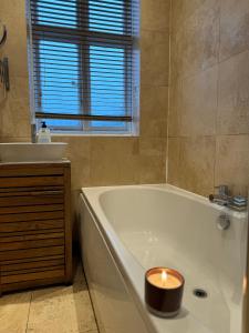 ein Badezimmer mit einer Badewanne mit Kerzen in der Unterkunft Didsbury GEM ! FREE ONSITE PARKING ! STYLISH & CENTRAL in Manchester