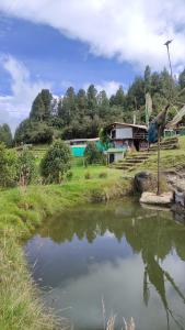 un estanque en un campo con una casa en el fondo en Bio Casa Colibrí, en Bogotá