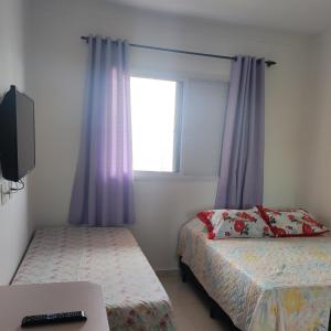 una piccola camera con due letti e una finestra di APARTAMENTO - GUILHERMINA - PRAIA GRANDE a Praia Grande