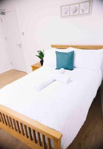 a large white bed with a blue pillow on it at 6 bedroom property in Sidcup