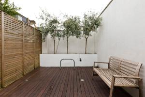 una terraza de madera con un banco y algunos árboles en Modern Town house in Barnes, West London, en Londres