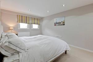 a white bedroom with a large white bed in it at Modern Town house in Barnes, West London in London