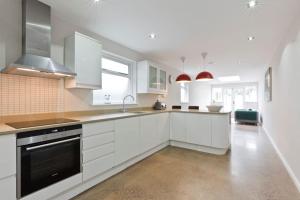 a kitchen with white cabinets and a stove top oven at Modern Town house in Barnes, West London in London