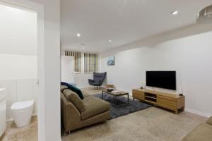 sala de estar con sofá y TV de pantalla plana en Modern Town house in Barnes, West London, en Londres