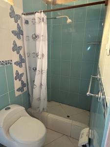 ein Bad mit einem WC und einer Dusche mit einem Duschvorhang in der Unterkunft LA CASA DE YOLA in Máncora