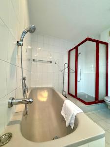 La salle de bains est pourvue d'une baignoire avec douche et d'un miroir. dans l'établissement Ferienhaus 80er Liebe mit Whirlpool, à Lustenau