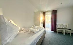 a bedroom with a bed with white sheets and a window at Ferienhaus 80er Liebe mit Whirlpool in Lustenau +18 photos