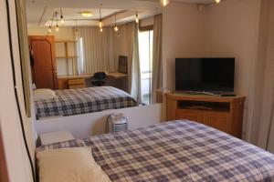 um quarto de hotel com duas camas e uma televisão em Mansão com Jacuzzi à 50m do Parque Barigui em Curitiba