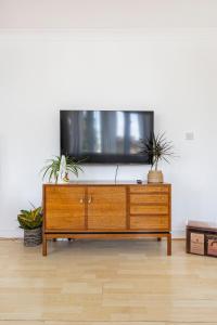 a tv on top of a wooden dresser in a living room at Loft-style apartment with large roof terrace in London