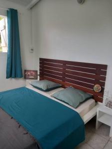 1 dormitorio con 1 cama con cabecero de madera en La Maison d'à Côté, maison 4 personnes en Le Gosier