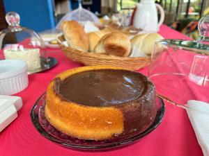 a chocolate cake on a table with a basket of bread at Pitaya Suítes in Cunha