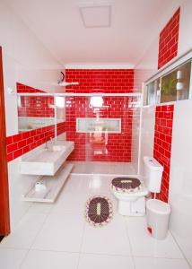 Baño de azulejos rojos con aseo y lavamanos en chácara do Rafael, en Pilar do Sul