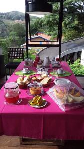 a table with a pink table cloth with food on it at Pitaya Suítes in Cunha