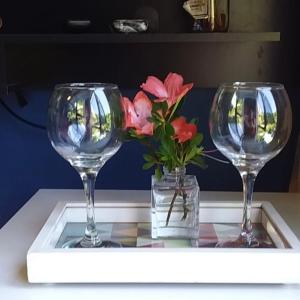 dos copas de vino y un jarrón con flores en una mesa en Pitaya Suítes, en Cunha