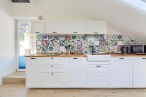una cocina con armarios blancos y una pared de azulejos en Un oblò sul mare, en Maiori