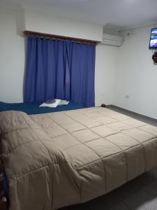 聖羅莎的住宿－Tesoro Escondido，一张大床,位于一个蓝色窗帘的房间