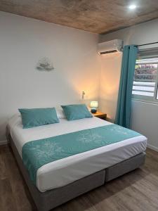 a bedroom with a large bed with blue pillows at Pension Irivai appartement "Uparu" 1 chambre bord de mer in Uturoa +129 photos