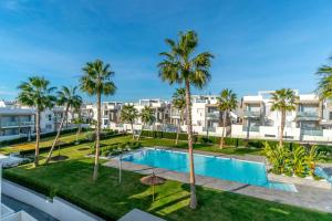an apartment with a swimming pool and palm trees at Apto. Residencial - Luxury - Wifi - SPA - Torrevieja - Orihuela Costa in Torrevieja
