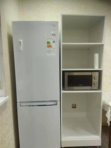La cuisine est équipée d'un réfrigérateur blanc et d'un four micro-ondes. dans l'établissement apart NUR, à Bishkek