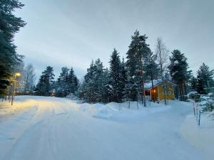 a road covered in snow next to a house at Lapland Forest Lodge in Rovaniemi