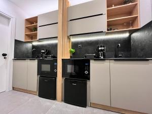 a kitchen with white cabinets and black appliances at Suite Rooms - Fine Living in Vévi
