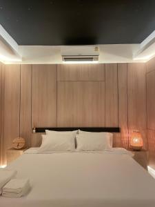 a bedroom with a large white bed with a wooden wall at Rema residence China town in Bangkok
