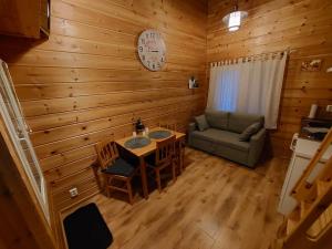 a room with a table and a couch and a clock at Lapland Forest Lodge in Rovaniemi