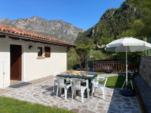 Un patio con una mesa y sillas y una sombrilla. en Casa Carla, bis 4 Personen, Garten, Balkon mit Blick auf den See und die Berge, en Crone