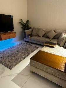 uma sala de estar com um sofá e uma televisão de ecrã plano em شقة دخول ذاتي em Taif