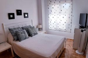 a bedroom with a bed with pillows and a window at Appartement Hola Playa Torrevieja in Torrevieja