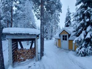 eine Hütte im Wald mit Schnee auf dem Dach in der Unterkunft Lapland Forest Lodge in Rovaniemi