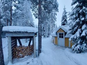 uma cabana na floresta com neve no telhado em Lapland Forest Lodge em Rovaniemi