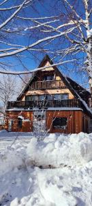 una grande casa in legno con neve di fronte di Pod Berdem a Wetlina