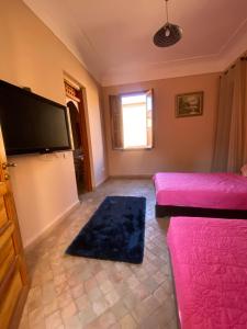 Elle comprend un salon doté d'un mobilier rose et d'une télévision à écran plat. dans l'établissement Villa les oliviers, à Marrakech