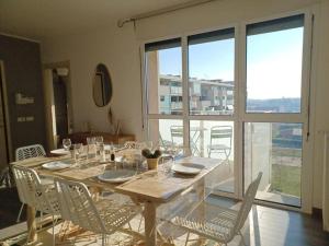 a dining room table with white chairs and a large window at Sui Generis penthouse with terraces in Milan