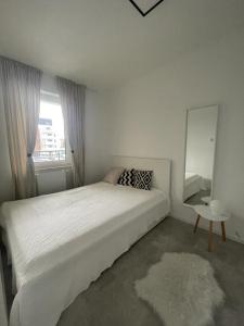 una camera bianca con un grande letto e uno specchio di Apartment Swinemünde a Świnoujście