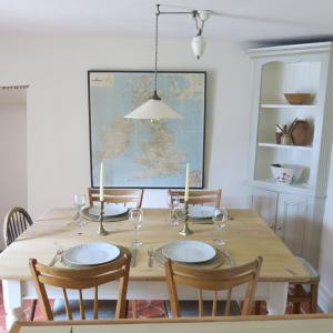 a dining room table with four chairs and a large painting at Characterful Cotswold cottage in Cirencester