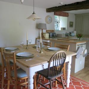 a kitchen with a wooden table with plates and glasses on it at Characterful Cotswold cottage in Cirencester