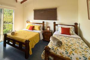 1 dormitorio con 2 camas y ventana en Arenal Lake House, en Nuevo Arenal