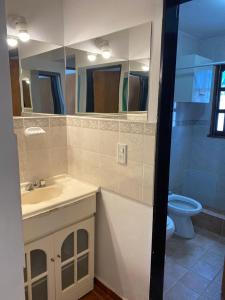 a bathroom with a sink and a toilet and a mirror at Cabaña El Hornero in Mina Clavero