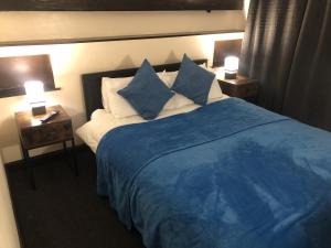 1 dormitorio con 1 cama grande con sábanas y almohadas azules en The Old Bath Arms, en Frome