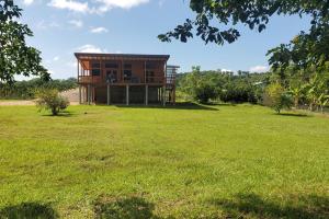 a large grassy field with a building in the background at Sanctuary at Paslow Falls-Belize in Bullet Tree Falls